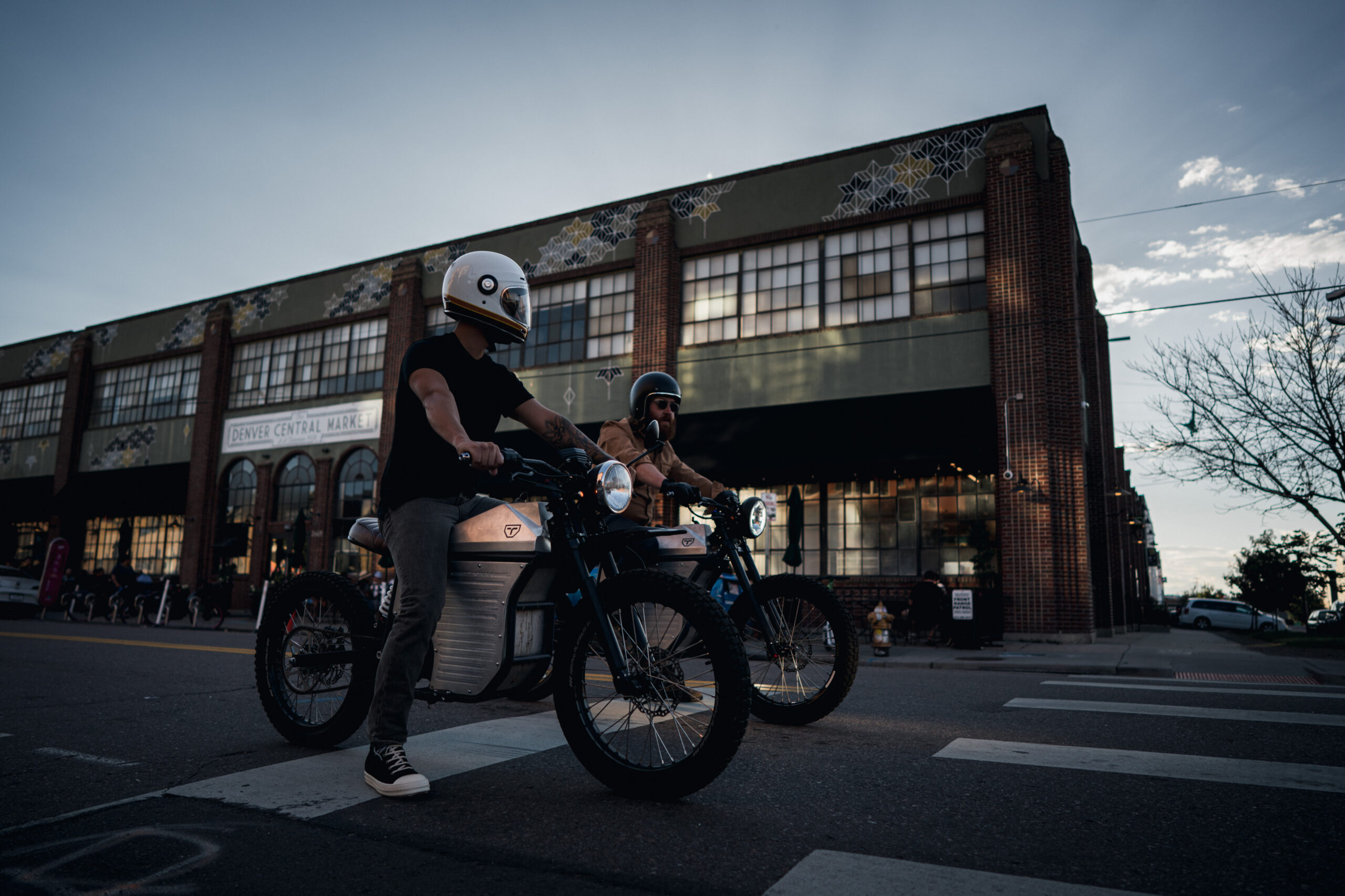 Two men are riding Terra Bikes, electric motorcycles in the streets of downtown Denver.